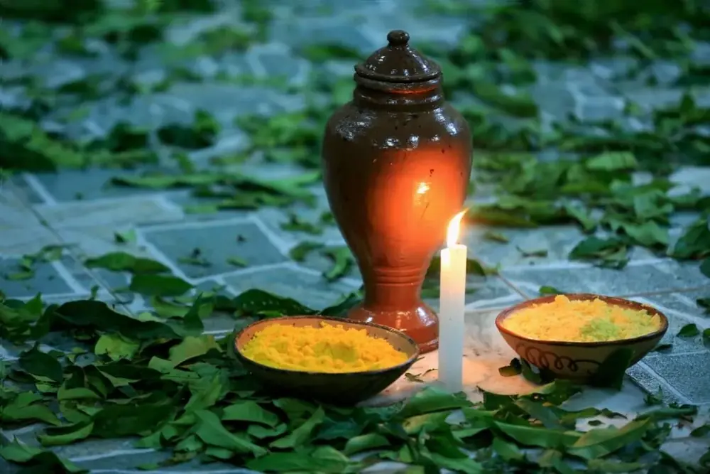 Oferenda com vela acesa e alguidares sobre folhas verdes